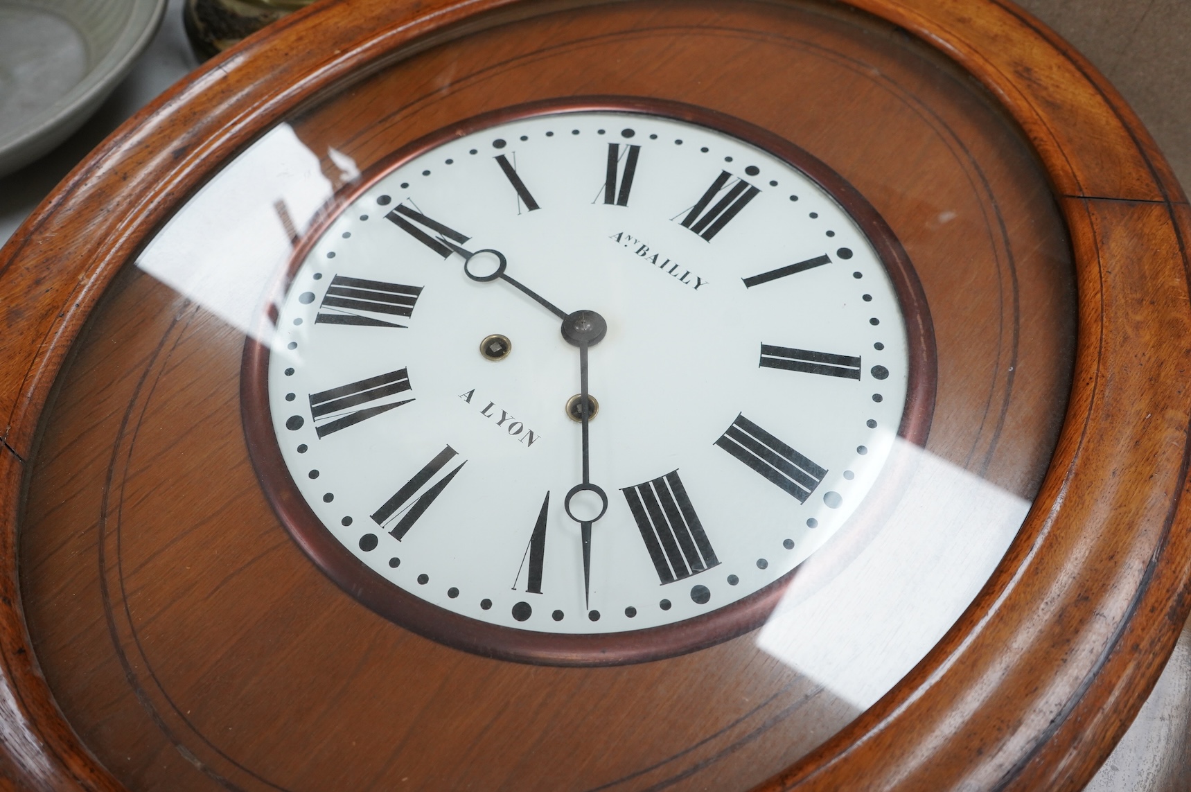 A French oak oval wall clock, the dial inscribed Any. Bailly A Lyon, with pendulum and key, 68cm high